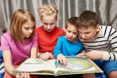 Niños pequeños reunidos alrededor de un libro.